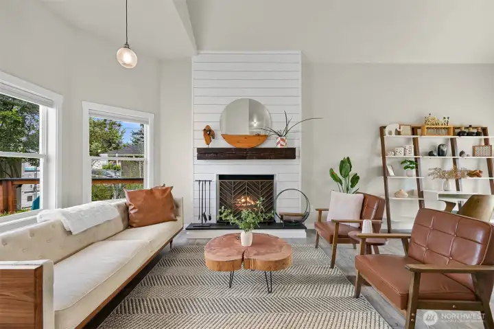 The bright, open living room features soaring ceilings, a shiplap fireplace accent wall, and large windows that fill the space with natural light.