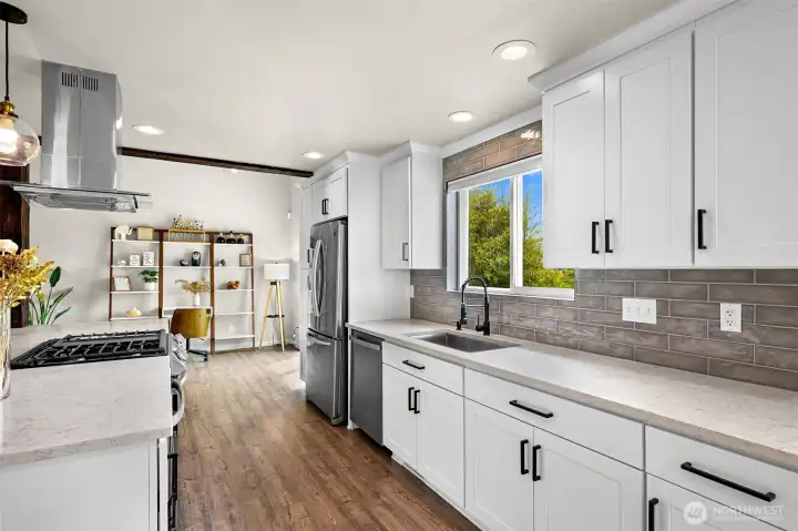 Prepare meals with ease in this well-appointed kitchen featuring quartz countertops, shaker cabinetry, subway tile backsplash, stainless steel appliances, and a window overlooking the backyard.