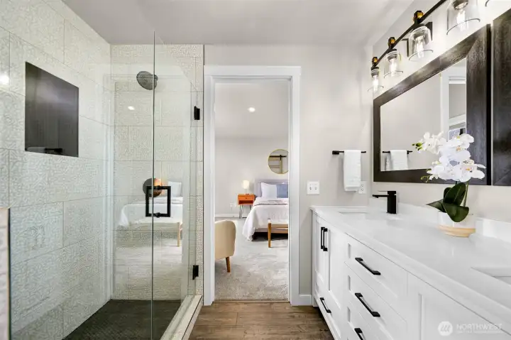 Spa-inspired primary bath featuring a walk-in tiled shower with frameless glass, designer patterned tile, matte black fixtures, and dual vanity setup.