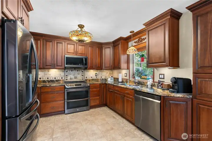 “Kitchen features black stainless steel appliances, cherry cabinets with soft-close drawers and pull-out shelves, and Tiffany lighting.” “Kitchen features black stainless steel appliances, cherry cabinets with soft-close drawers and pull-out shelves, and Tiffany lighting.”
