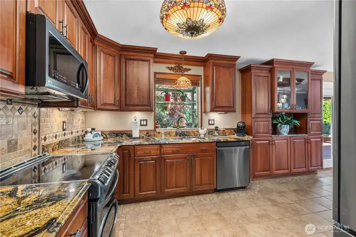 “Kitchen features a greenhouse window, built-in china cabinet, exotic granite countertops, and a custom backsplash.” “Kitchen features a greenhouse window, built-in china cabinet, exotic granite countertops, and a custom backsplash.”