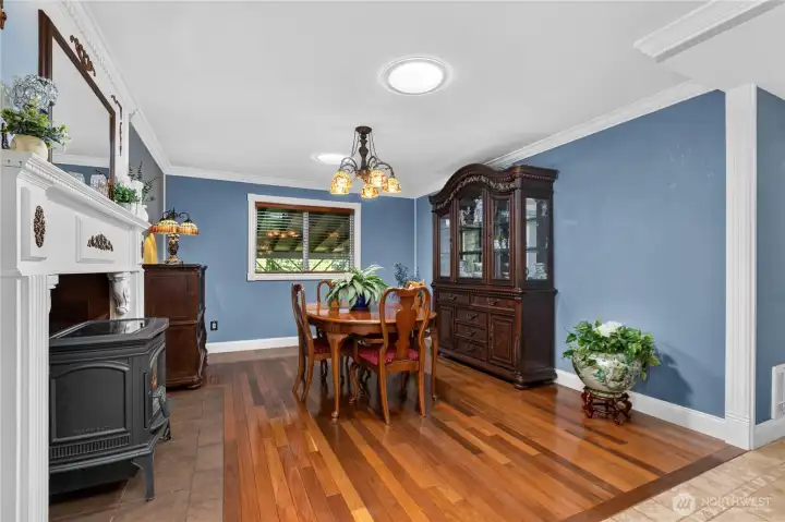 “Dining room featuring a Lopi pellet stove, custom mantel, Tiffany chandelier, wood-wrapped window, and Levolor wood blinds.” “Dining room featuring a Lopi pellet stove, custom mantel, Tiffany chandelier, wood-wrapped window, and Levolor wood blinds.”