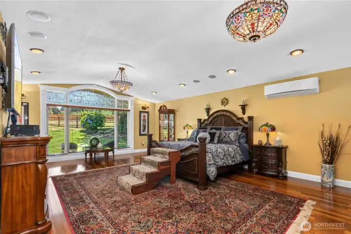 “Spacious 700-square-foot primary suite featuring recessed lighting, ceiling speakers, a picture window, and Tiffany lighting.” “Spacious 700-square-foot primary suite featuring recessed lighting, ceiling speakers, a picture window, and Tiffany lighting.”