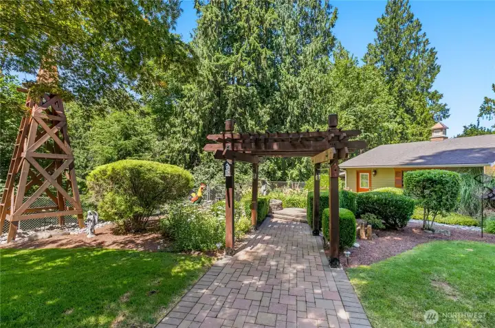 “Landscaped grounds featuring a brick pathway, arbor, ponds, bridge, and windmill.” “Landscaped grounds featuring a brick pathway, arbor, ponds, bridge, and windmill.”