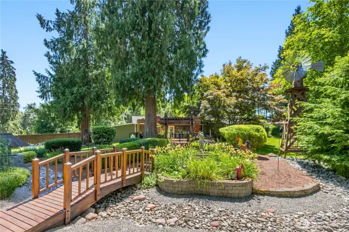 “Custom bridge overlooking the landscaped pond, with a view toward the home." “Custom bridge overlooking the landscaped pond, with a view toward the home."