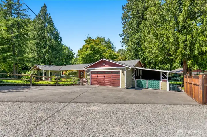 “Another view of the home showcasing new custom insulated garage doors, a carport, and a generator.” “Another view of the home showcasing new custom insulated garage doors, a carport, and a generator.”