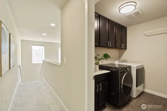 Laundry room boasts upper cabinets for bonus storage.