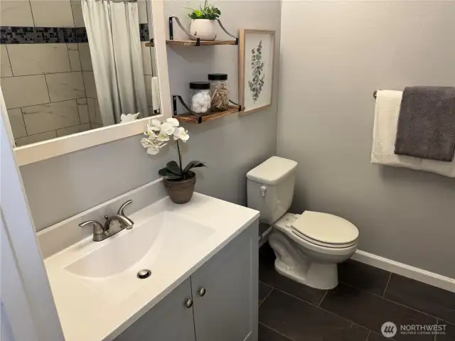 Hall bathroom has beautiful tub and tile, radiant heated slate floors, and a new vanity.