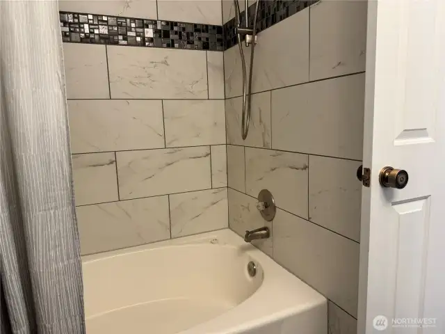 Oversized bathtub in the hall bath is surrounded by beautiful tile work.