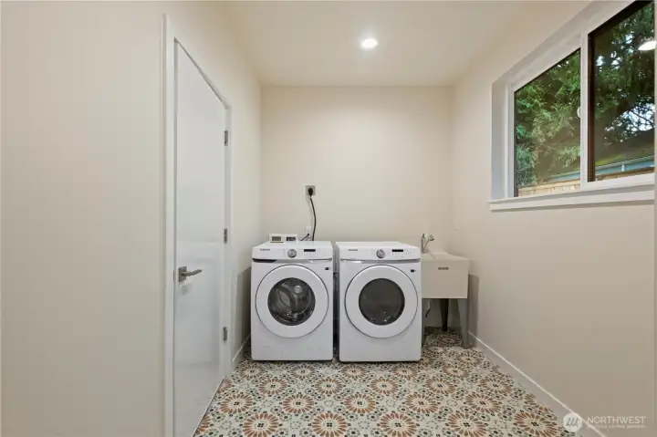Spacious laundry room with heated tile floors connects the garage and the kitchen. Perfect place to store boots and coats!