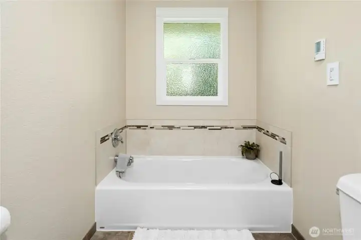 A soaking tub with a privacy window — natural light without sacrificing a thing. The kind of bathroom moment you stop rushing through