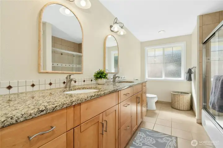 Granite counters, warm wood cabinetry, and an arched mirror that makes the whole vanity feel intentional. The window keeps it from ever feeling dark