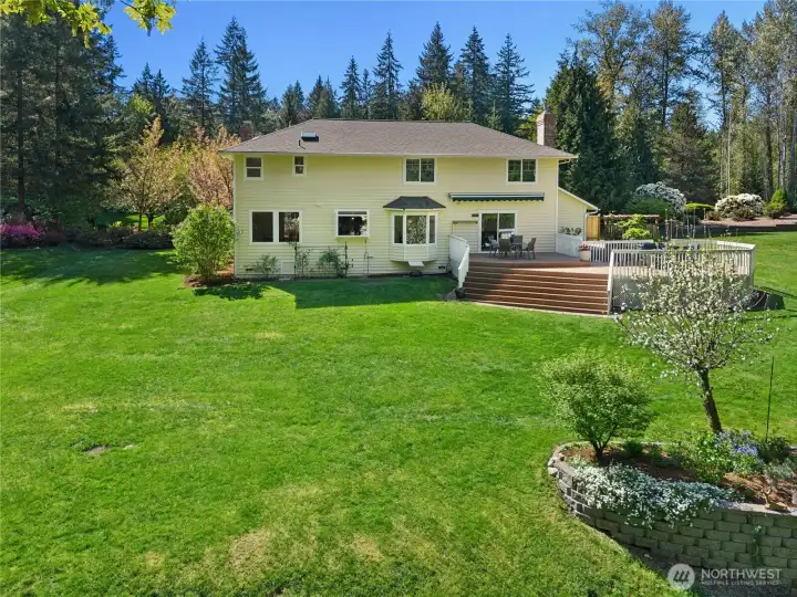 The rear of the home tells its own story — deck off the main living area, stairs down to the yard, and enough green space that you never feel like you're on top of your neighbors.