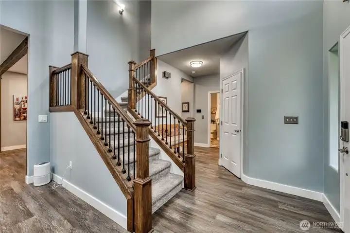 Entry way with updated laminate flooring, carpet and newer railing system on the stairs.