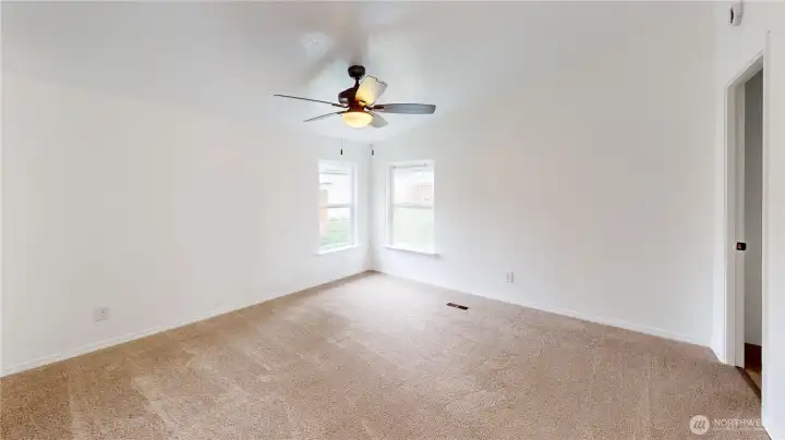Spacious primary suite with vaulted ceiling, new carpet, large closet, ceiling fan and private bathroom.