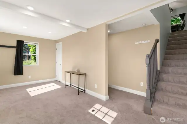 Light-filled lower-level space with fresh carpet, recessed lighting, and direct access to the upper floor.