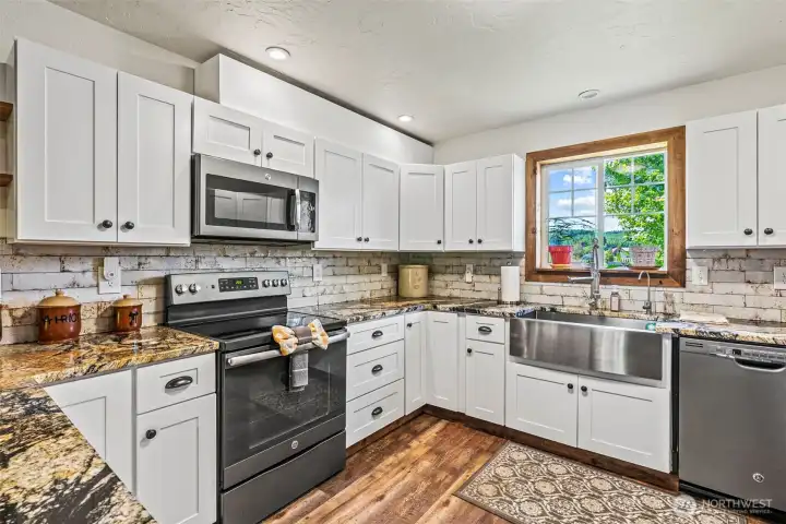 Light bright, well appointed kitchen with white cabinetry, stainless appliance package and fitting farm sink.