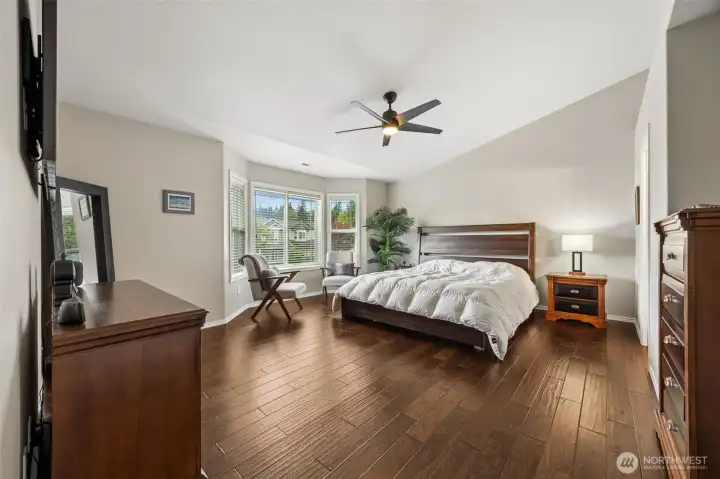 Primary bedroom with vaulted ceiling, ceiling fan and bay window.