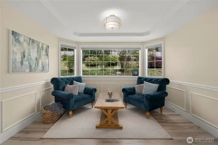 Elegant formal dining room featuring classic wainscoting and stunning coffered ceilings, currently styled as a sophisticated sitting room offers flexible living space.