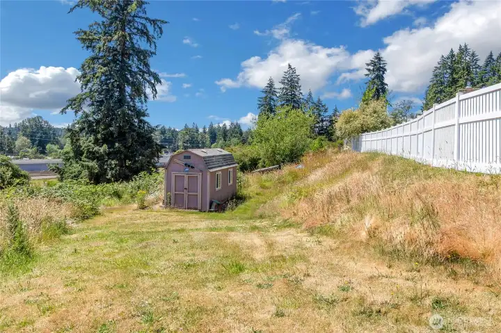 Another view of storage shed and vinyl fence