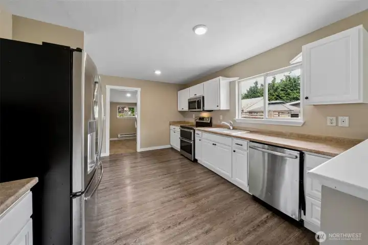 Kitchen with dishwasher, fridge, electric stove/range. Cabinets freshly painted with new hardware added.