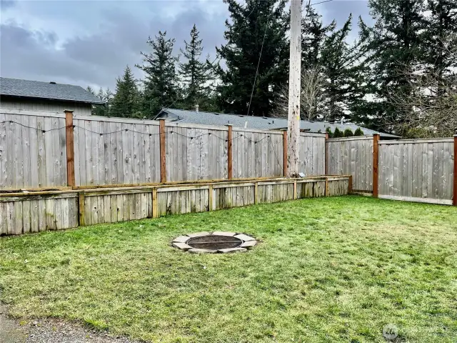 Yard featuring planter boxes and an in-ground firepit, creating a perfect outdoor space for gardening, relaxation, and gatherings.