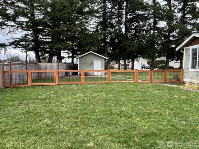 Other side of the home featuring a view of the fence and a 1-car garage/shop, set on a huge lot with plenty of space for outdoor activities and potential projects.