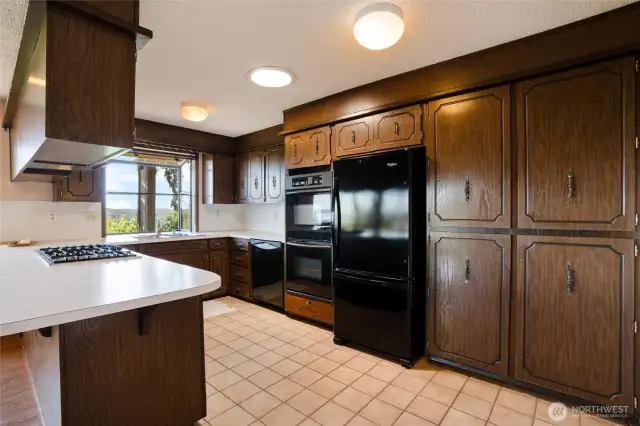 A nice-sized kitchen includes tile flooring, a gas cooktop, double ovens, and views of the Olympics and Henderson Bay.