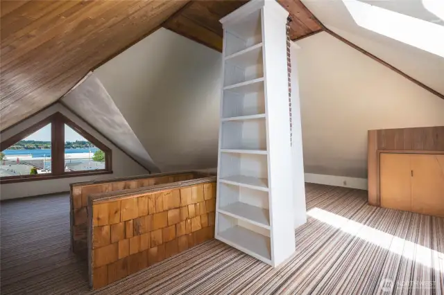 High above it all, this third floor flex space is perfect for a library, "hang out" space. It offers stunning water views, skylights, custom shelving and storage space.