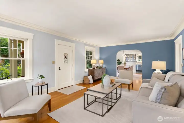 A welcoming living space framed by original millwork, wood-trimmed windows, hardwood floors and a coved doorway that leads to the dining room.  It's a seamless connection to the home’s architectural roots.