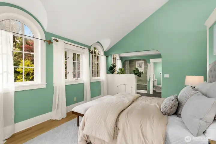 Graceful arched windows frame lush greenery and guide the view toward the spa-inspired ensuite bath with handcrafted tile shower.