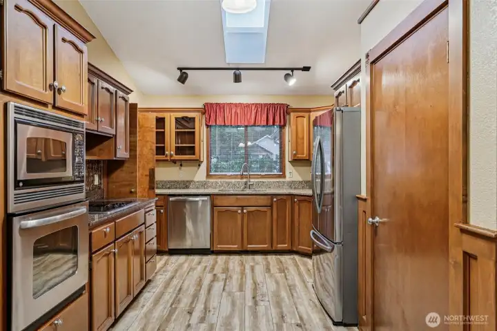 Spacious and bright kitchen with plenty of storage, stainless steel appliances, a pantry, and skylights.