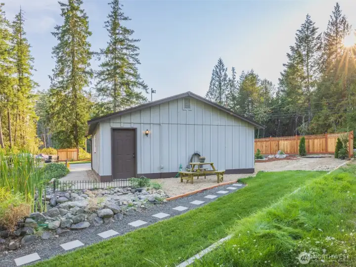Detached garage steps away from the home with an office, or studio with landscaping like a park.