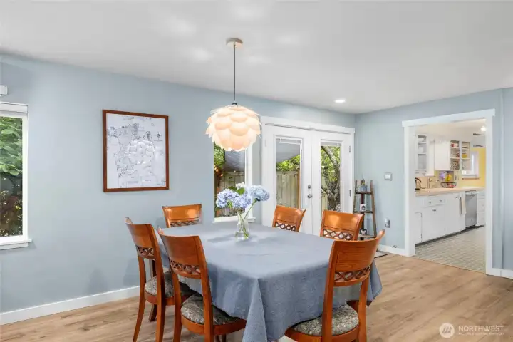 Formal dining area with LVP floors, fresh paint and trim. French doors allow you to take in the curated gardens.