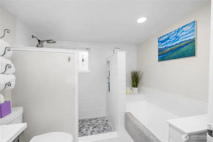 Another view of the primary ensuite bathroom with soaking tub and walk-in tiled shower.