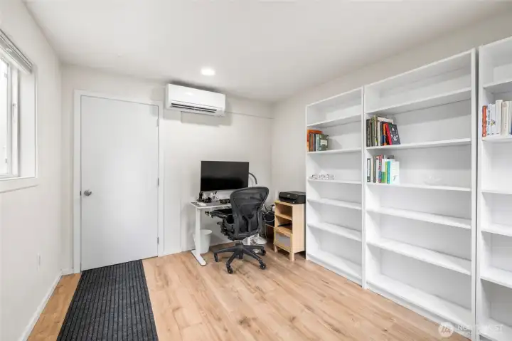 Seperate office space just off the garage with shelving units, heat/AC and LVP flooring. You could put a door through behind the shelving to connect to the ADU if desired.