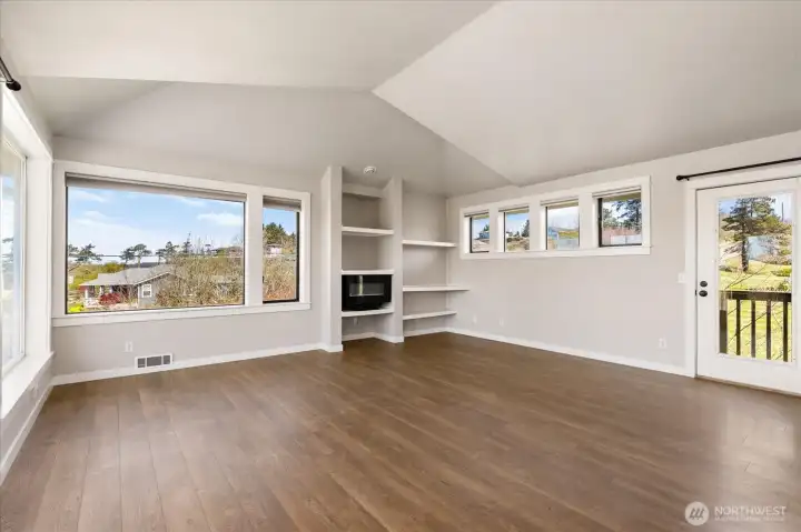 The far end of the living room has shelving nooks with an electric fireplace. To the right is the backdoor.
