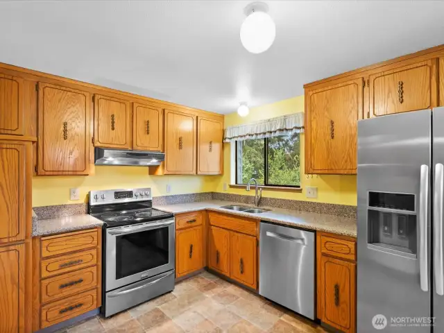 Slab granite counters & SS appliances in kitchen.