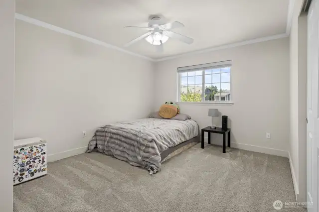 Fourth bedroom with crown molding, ceiling fan, and updated carpet and trim