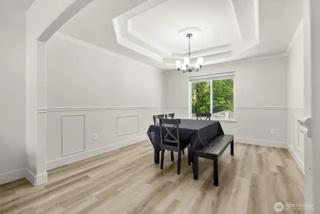 Formal dining room with ornate tray ceiling and chair-rail molding