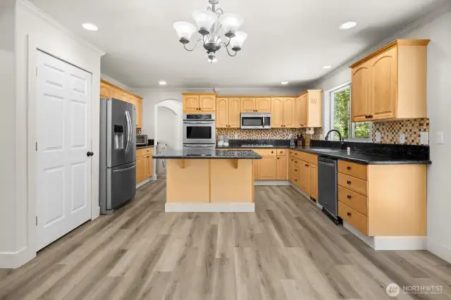 Updated kitchen featuring an oversized island with seating, granite countertops, gas cooktop and full-size double wall ovens. Stainless steel kitchen appliances all stay.