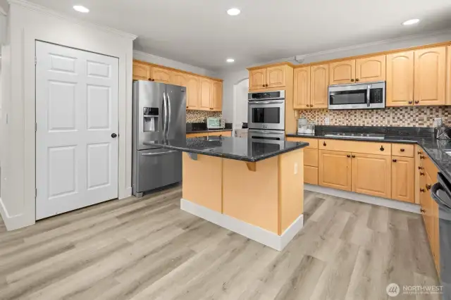 Updated kitchen featuring an oversized island with seating, granite countertops, gas cooktop and full-size double wall ovens. Stainless steel kitchen appliances all stay.