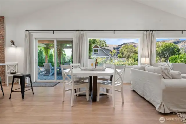 Light-filled great room with modern designer furnishings, neutral tones, and a wall of windows that open the home to surrounding views and sunshine