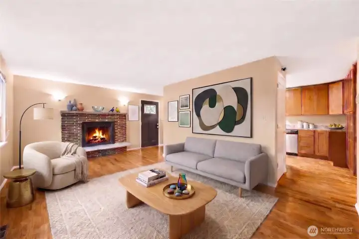 Bright, open concept living room featuring refinished hardwood floors, large windows, and a cozy fireplace—showcasing the home’s spacious layout and updated interior design