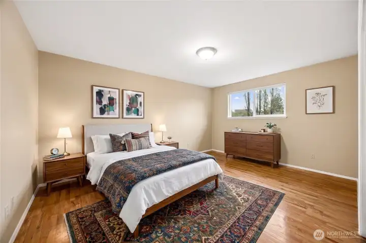 Spacious primary bedroom with updated flooring, neutral paint, and abundant natural light—creating a peaceful retreat within the home
