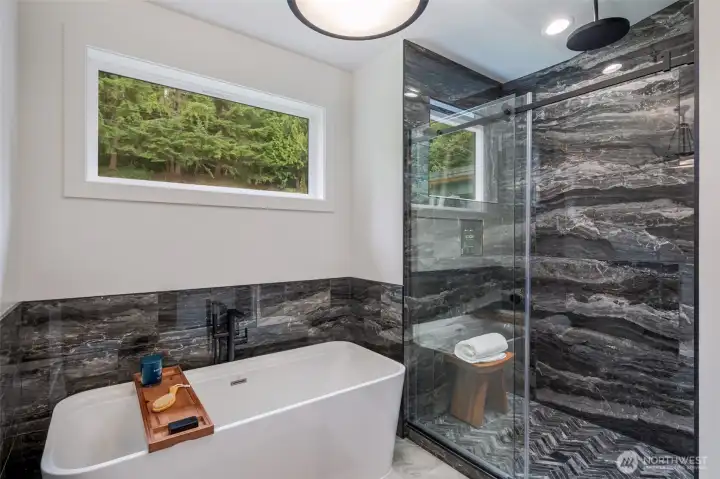 Free standing soaking tub with large marble styled shower and rain fixture overhead
