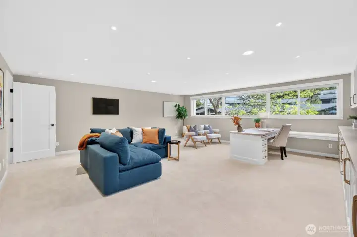A sprawling family room that works as hard   as it relaxes — custom white cabinetry spans   the full wall with a generous built-in desk,   glass-front uppers, and counter storage that   makes this equally suited as a home office,   homework hub, or media room