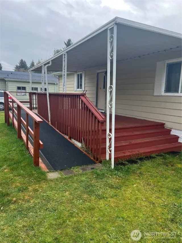 Large, covered deck with ramp and space to put a picnic table and lounge chairs.