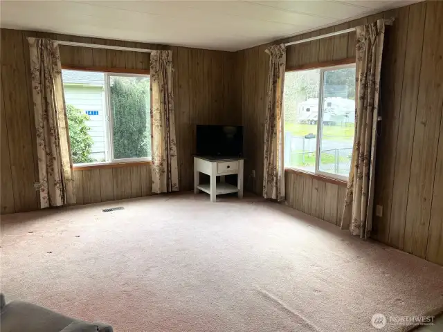 Living room with windows on side and front of home.