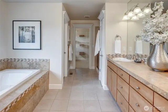 The primary bath is large and luxurious, featuring a deep soaking tub, dual vanities, a separate tiled shower, and a private commode.